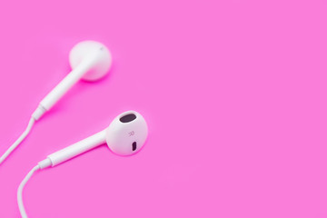 White earphones on pink background with copy space and clipping path. Flat lay. Top view.