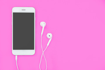 Smartphone with Earphones on pink background with copy space and clipping path. Flat lay. Top view.