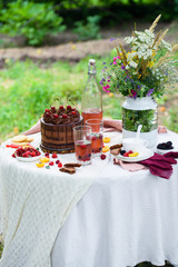Summer picnic on nature, with a delicious chocolate cake, compote, berries, wild flowers