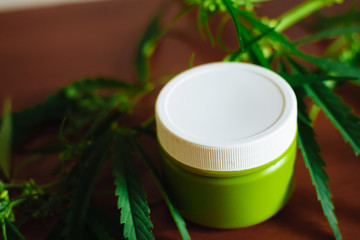 Cannabis hemp cream background with marijuana leaf - cannabis concept self care in of health care. Cosmetics with hemp extract on table. Herbal organic medicine CBD product