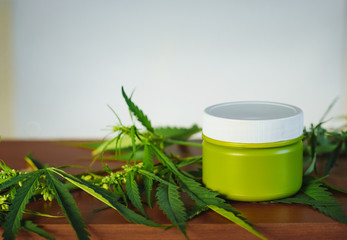 Cannabis hemp cream background with marijuana leaf - cannabis concept self care in of health care. Cosmetics with hemp extract on table. Herbal organic medicine CBD product
