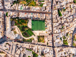Football field surrounded by stone city. Turkey Malta. Aerial top view