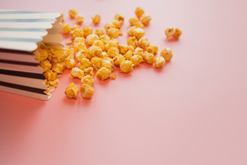 Fototapeta premium Popcorn in paper bag scattered on pink background top view