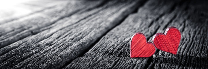 Banner Of Two Red Wooden Hearts On Dark Wooden Table With Sunlight