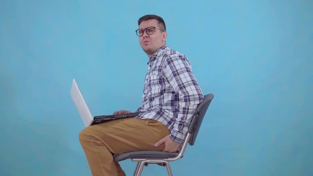 man sitting working on a laptop is experiencing pain and discomfort from hemorrhoids close up