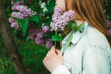 girl holding a sprig of purple lilacs, close-up
