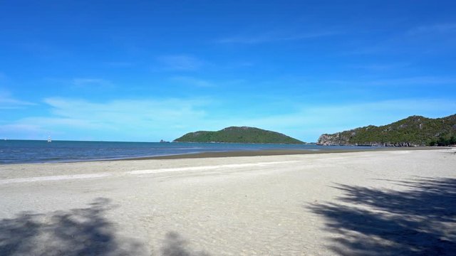 Slow pan across beautiful golden sands and blue seas in Thailands tropical coastline