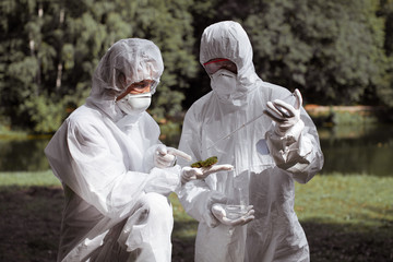 Ecological problem. Pollution. Examine soil. Scientist in protective mask and suit taking water...