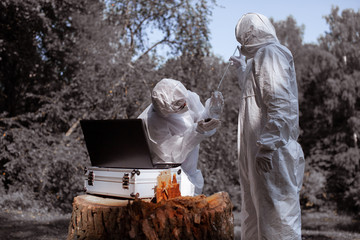 Ecological problem. Pollution. Examine soil. Scientist in protective mask and suit taking water...