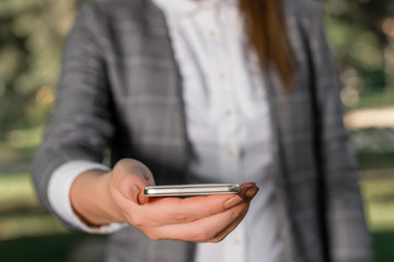 Woman in grey suites holds mobile phone.