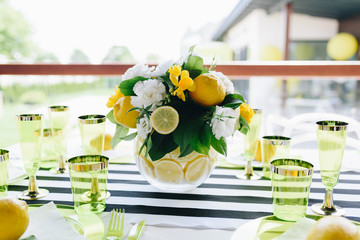 A bouquet of flowers with lemons in a glass vase on a festive table indoors