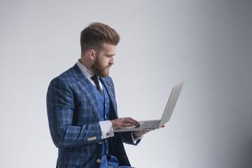 side view of concentrated businessman in armchair working on laptop. isolated on grey