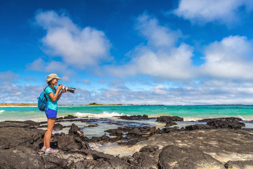 Ecotourism tourist photographer taking wildlife and landscape photos on Galapagos Islands. Woman...