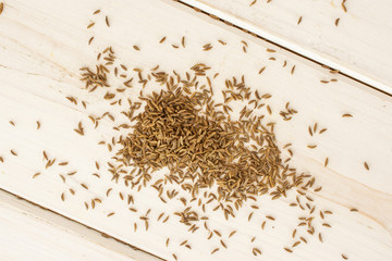 Lot of whole dry caraway fruits flatlay on white wood