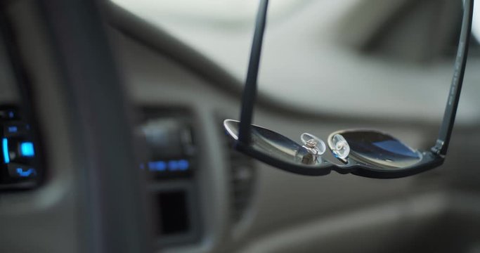 Sunglasses Hanging From Rear View Mirror in Car
