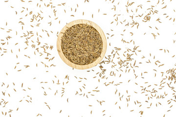 Lot of whole dry caraway fruits in a wooden bowl flatlay isolated on white background