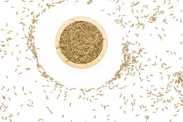 Lot of whole dry caraway fruits in a wooden bowl flatlay isolated on white background