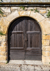Fototapeta na wymiar Rustic brown wooden door and stone arch