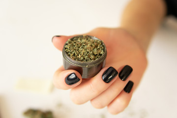 Close up of marijuana blunt with grinder. Woman preparing and rolling marijuana cannabis joint....
