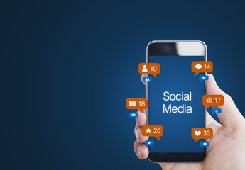 Hand holding mobile smart phone, with social media and social network notification icons, on blue background