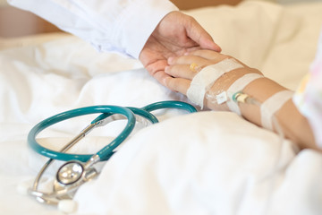 Doctor and child patient in hospital concept. Hand of kid physician philanthropy holding illness illness inpatient lying on hospital bed with chart and stethoscope