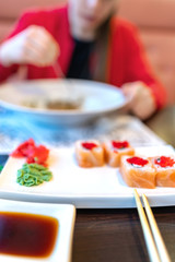 girl eating pasta and sushi, blur. without a face. lunch, meal in the restaurant. vertical. red clothes, sushi Philadelphia