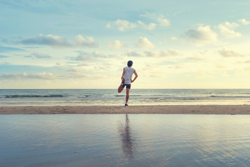 young  man with fit strong body training on beautiful Summer sunset beach sand running barefoot in sport well being and healthy lifestyle concept