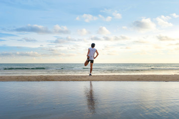 young  man with fit strong body training on beautiful Summer sunset beach sand running barefoot in sport well being and healthy lifestyle concept
