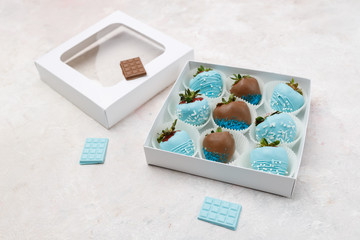 Delicious ripe strawberries in brown and blue chocolate packed in a gift box