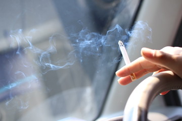 運転をしながら車内で喫煙をする男性の手元。