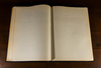 Opened ,old, aged , yellow, blank book pages on dark brown wood background.