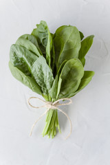 Bunch of fresh spinach leaves in the center on a light gray background. Healthy organic food. Vegetarian diet greens. Top view, copy space, close-up.