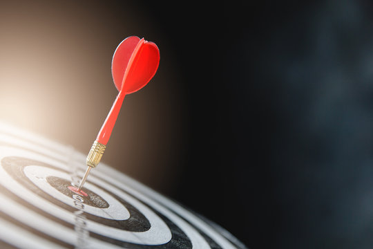 Dart arrow hitting in the target center of dartboard,business target