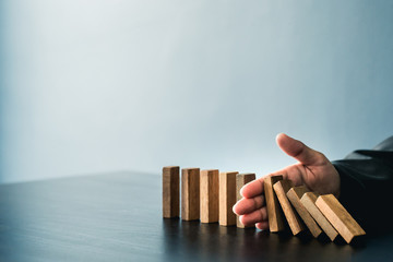 Close up of businessgirl hand Stopping Falling wooden Dominoes effect from continuous toppled or risk, strategy and successful intervention concept for business.