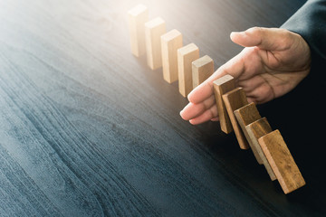 Close up of businessgirl hand Stopping Falling wooden Dominoes effect from continuous toppled or risk, strategy and successful intervention concept for business.