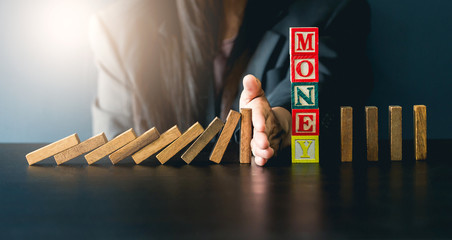 Close up of businessgirl hand Stopping Falling wooden Dominoes effect from continuous toppled or...