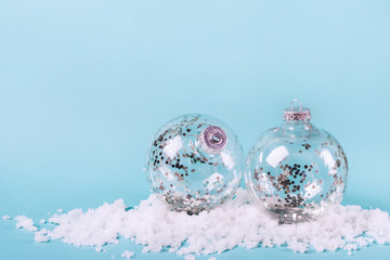 Transparent balls with silver confetti in snow. Minimalistic Christmas Concept