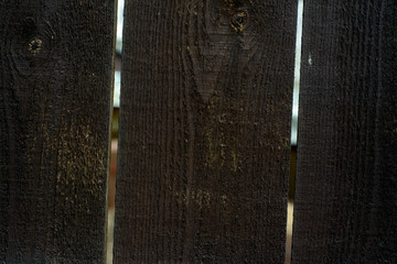 Dark background from wooden boards of natural color. Light is visible through the gaps between the boards.