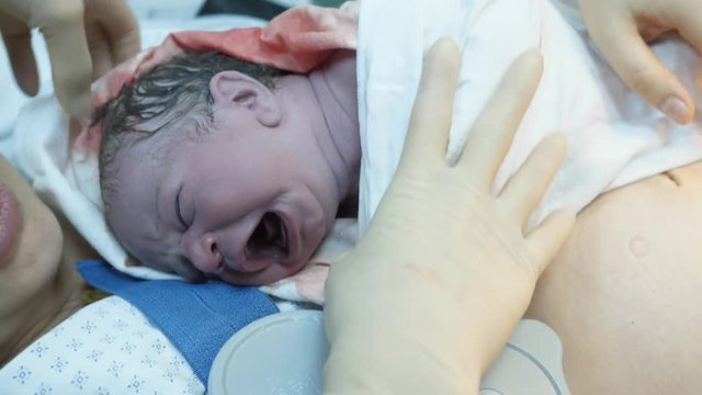 Portrait of just newborn baby child on mother arms, nurse hands swaddle child, magic moment of priceless mother and baby emotional bond