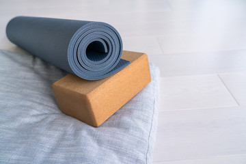 Yoga mat, cork block meditation pillow eco-friendly sustainable fitness products shopping. Natural organic material props for wellness studio on wooden floor background.