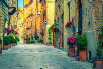 Brick and stone houses decorated with colorful flowers, Pienza, Italy