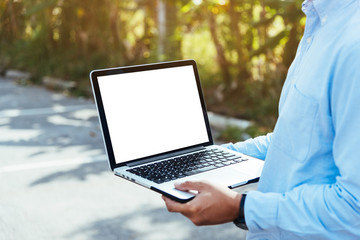 Asian man civil engineer holding a blank white screen laptop at contruction site..