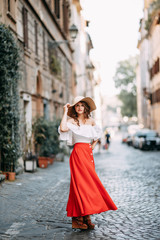 Portrait of a girl in a red dress and hat. Stylish bride on the streets of Rome.