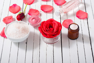perfume, body care and beauty products with red roses, pink petals on white wood table