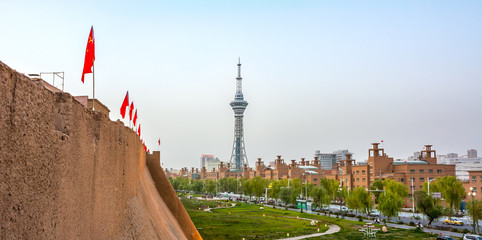 Flags lining Kashgar's renovated Old City wall, with view of a park, tower, and Tuman Rd.  Kashgar, Xinjiang China. - obrazy, fototapety, plakaty