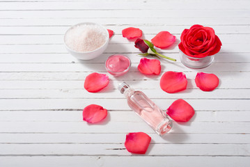 perfume, body care and beauty products with red roses, pink petals on white wood table