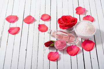 perfume, body care and beauty products with red roses, pink petals on white wood table