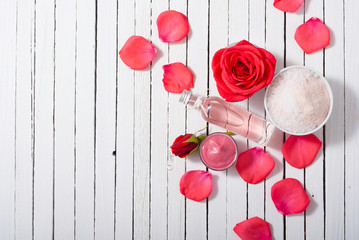 perfume, body care and beauty products with red roses, pink petals on white wood table