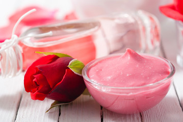 perfume, body care and beauty products with red roses, pink petals on white wood table