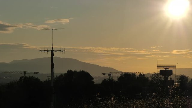 Silhouetted view of an all-around antenna for air defense and tracking made of phased array technology on a rotating platform, with mountains in the background